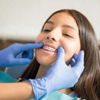 a patient with braces brushing their teeth