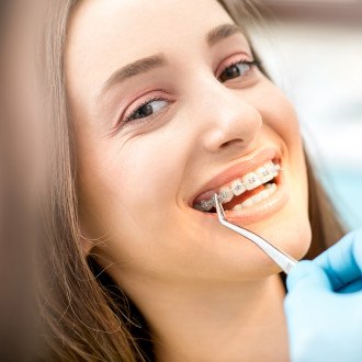 a patient with braces brushing their teeth