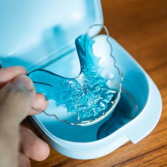 a patient with braces brushing their teeth