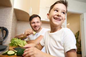 a child with braces smiling while preparing his lunch